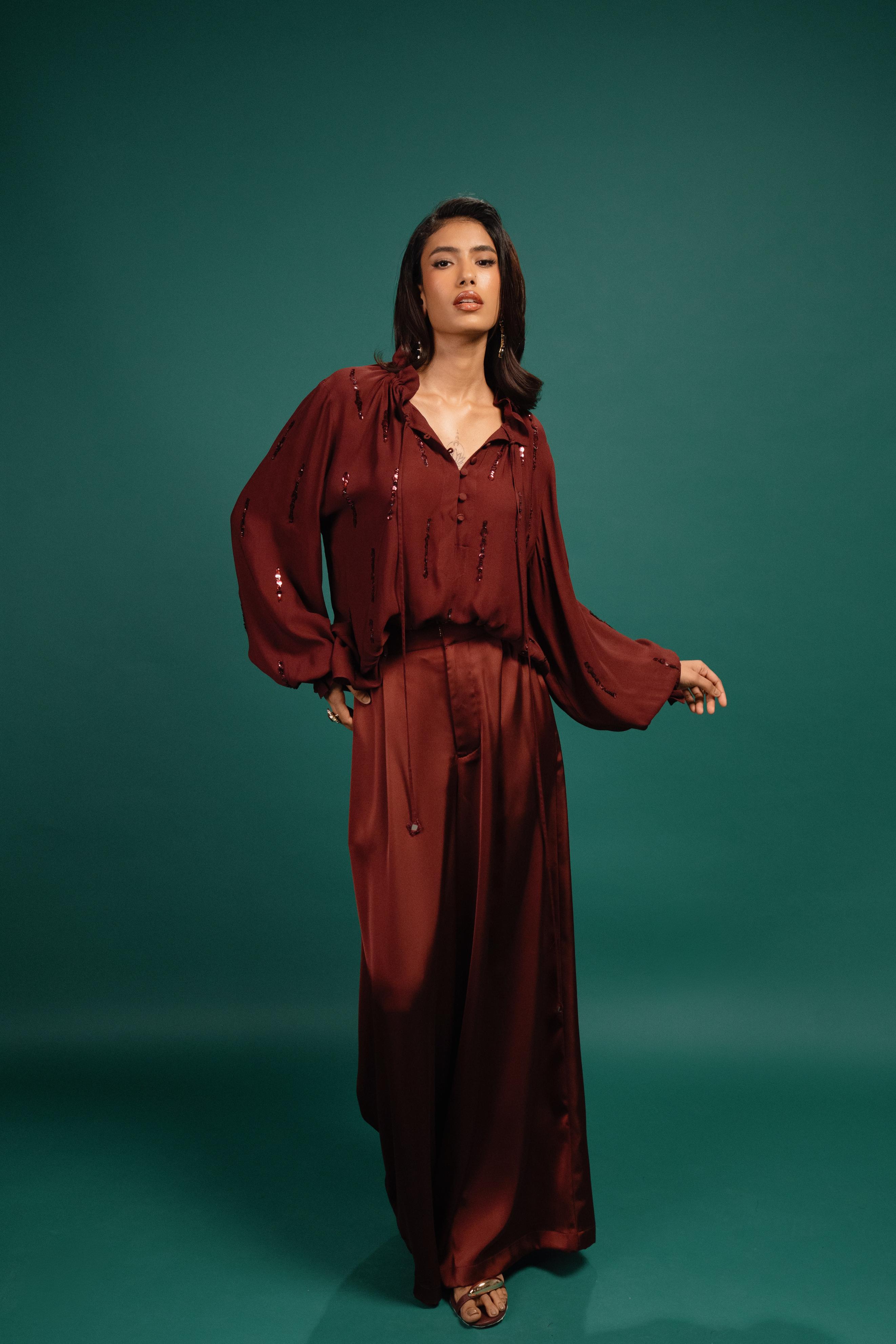 Woman wearing a burgundy outfit against a teal background