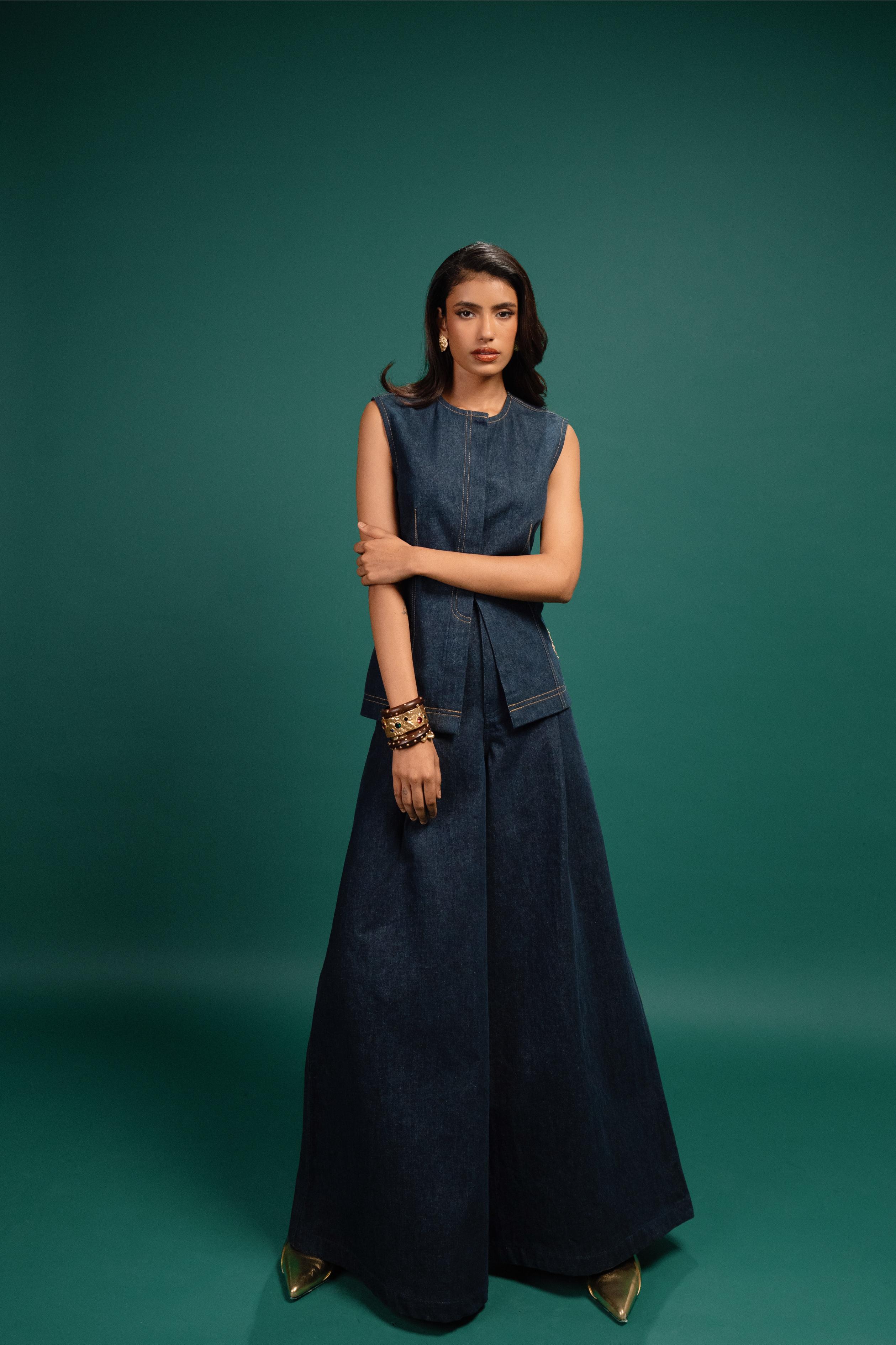 Woman wearing a dark blue denim dress against a teal background