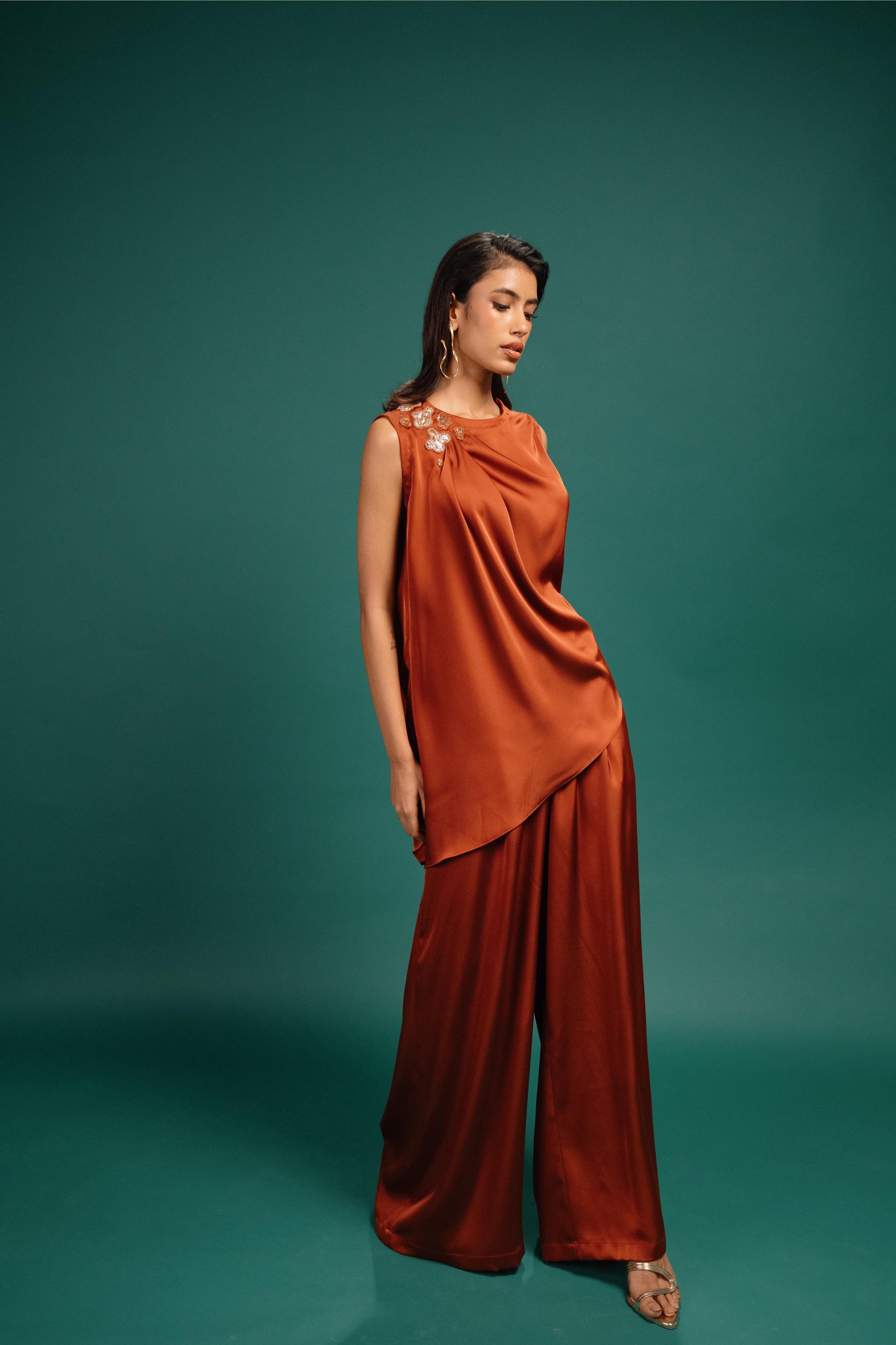 Woman wearing a rust-colored outfit against a teal background