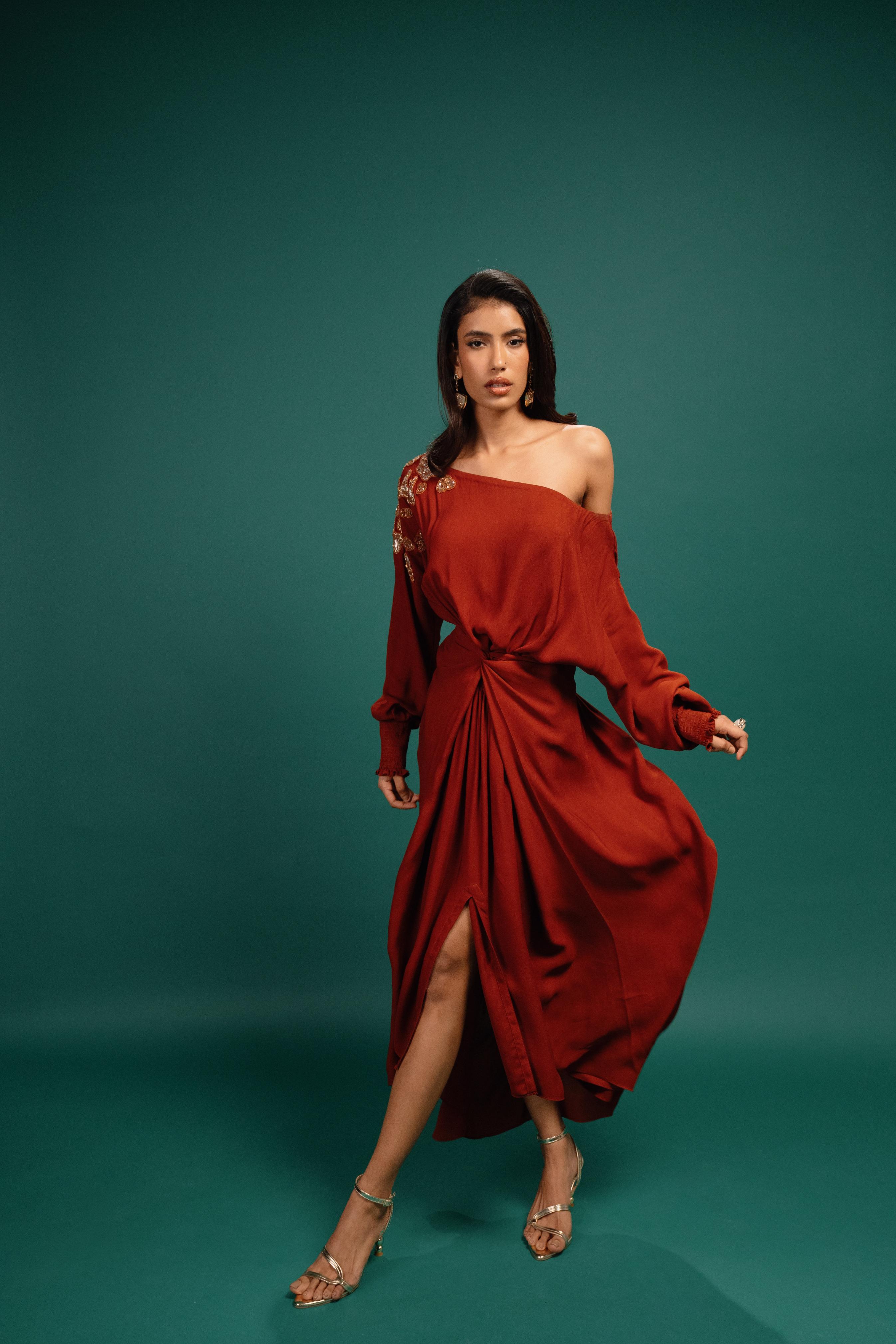Woman wearing a red off-shoulder dress against a teal background